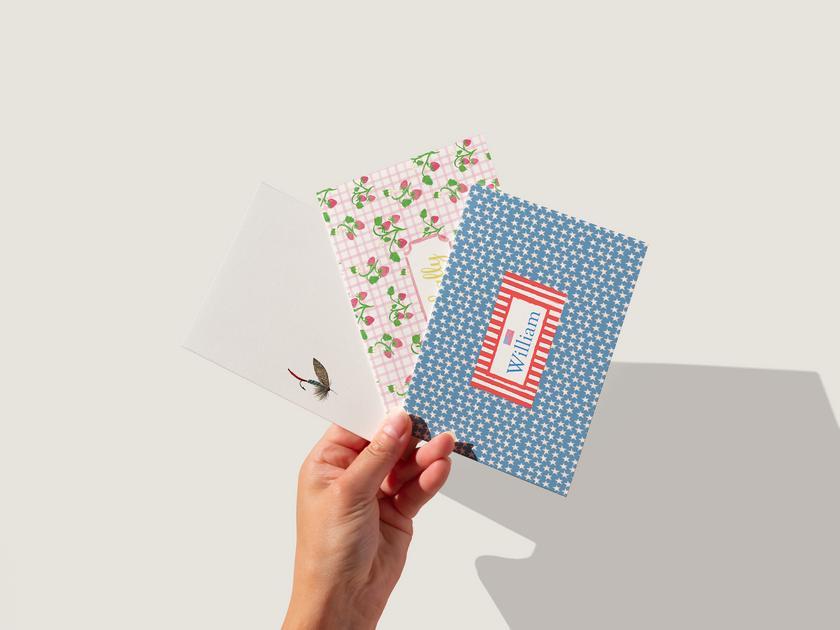 Hand holding a blue polka dot notebook with floral and plain designs on a light gray background